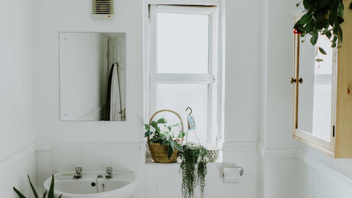 A white bathroom with a ceiling light above the bath