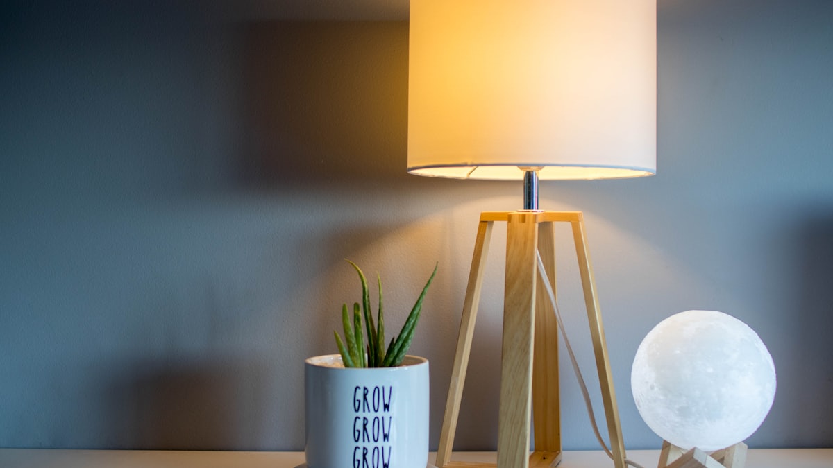 A warm table lamp glowing beside a moon lamp